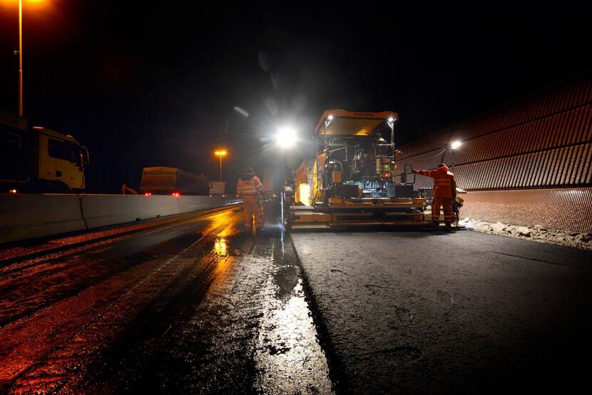 Wegwerkers in de nacht bezig met asfalteren